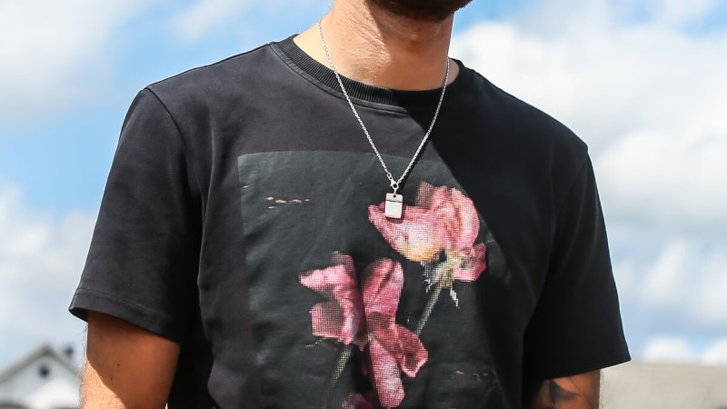 Speedway-Fahrer mit Kappe und Sonnenbrille vor blauem Himmel